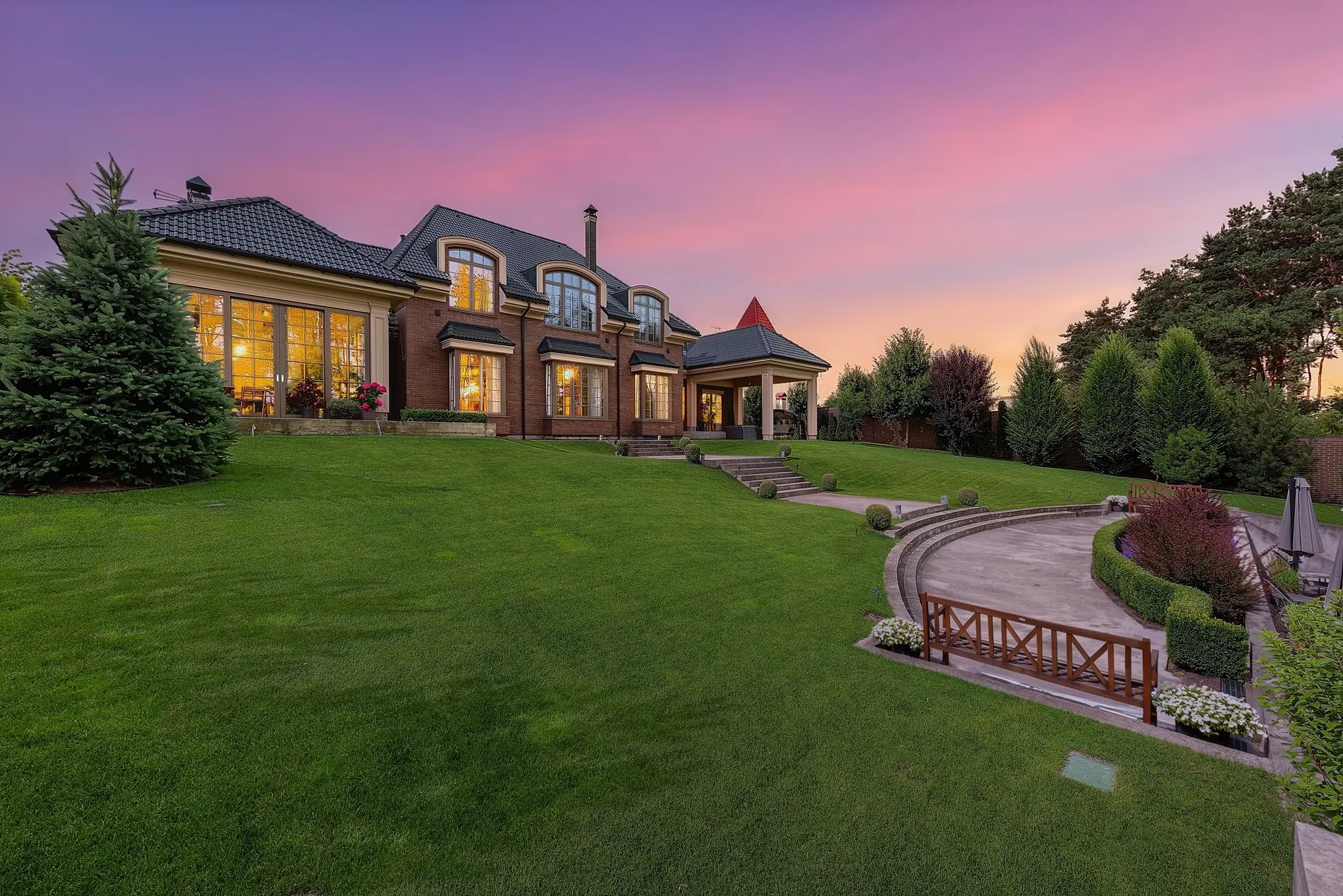 Brick manor house with a large lawn turned from a daytime photo into a twilight shot with glowing windows by Stager AI