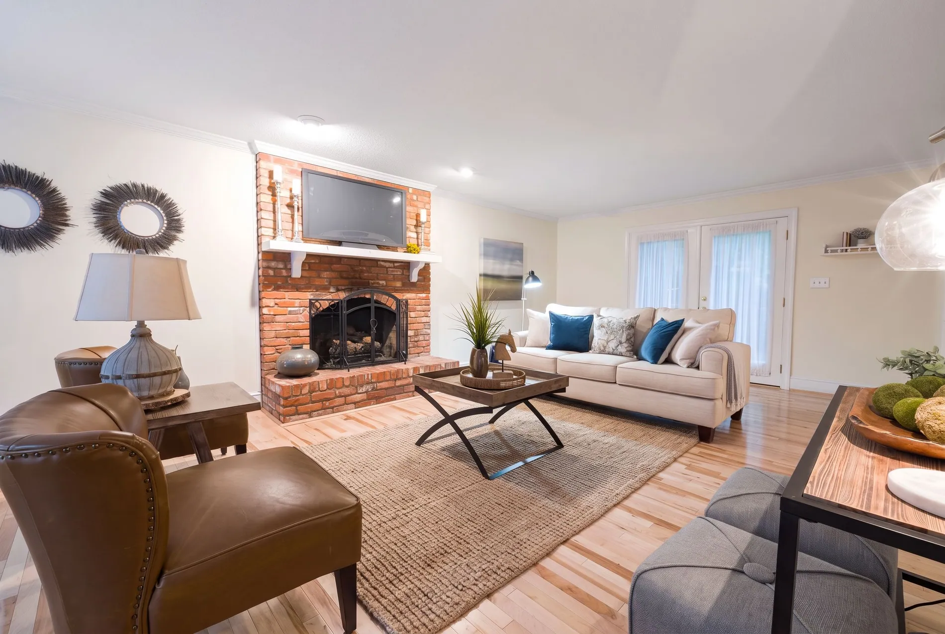 Bright living room with a red brick fireplace, empty before and with a warm fire added by Stager AI after