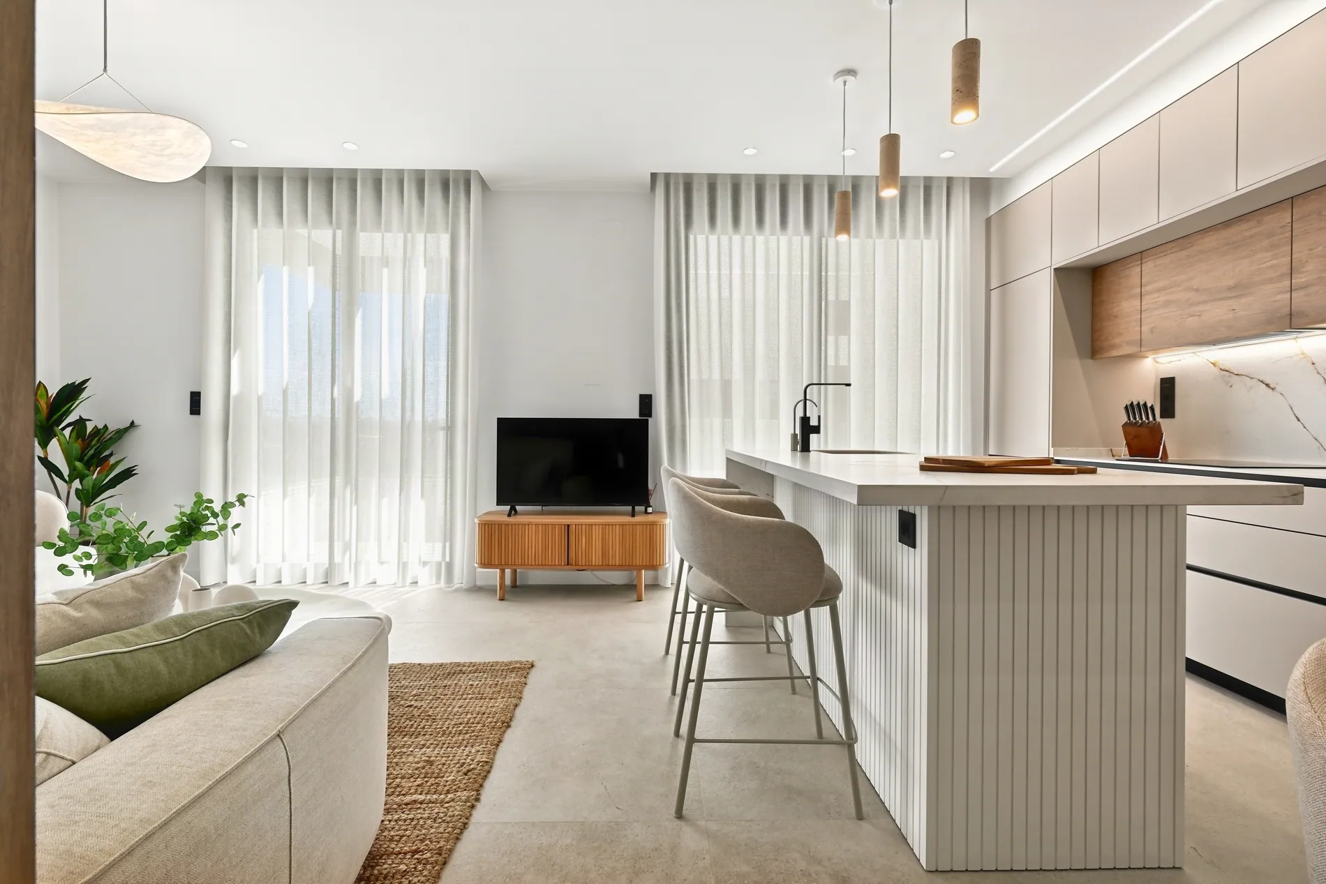 Bright open-plan living room and kitchen with sheer curtains, edited with Stager AI HDR