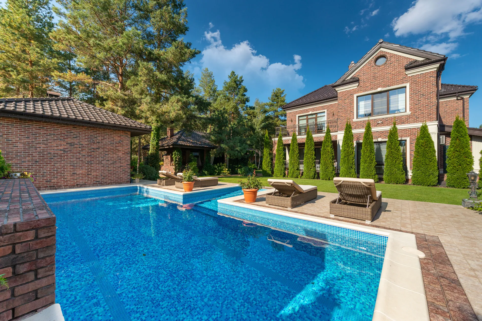 Brick house and pool under a heavy grey sky, replaced by a deep blue sky with soft clouds