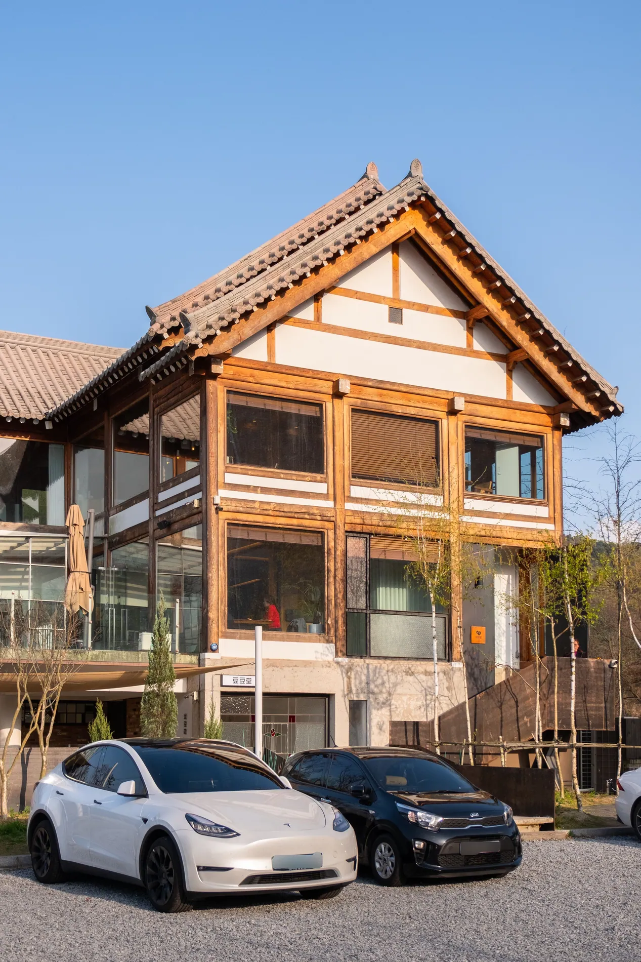 Timber house with two cars parked in front, front license plates blurred by Stager AI